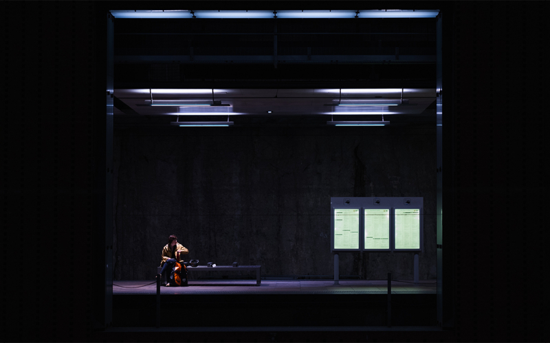 een vrouw zittend op een perronbank van een treinstation (© Edith Coen | dwars) 