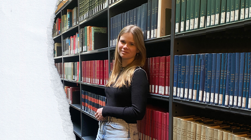 Julie leunt tegen een boekenkast in de bib